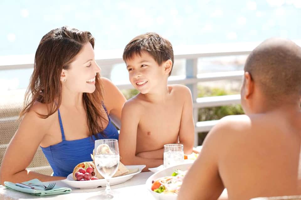 Mother and children dining together on a beachfront terrace overlooking the ocean