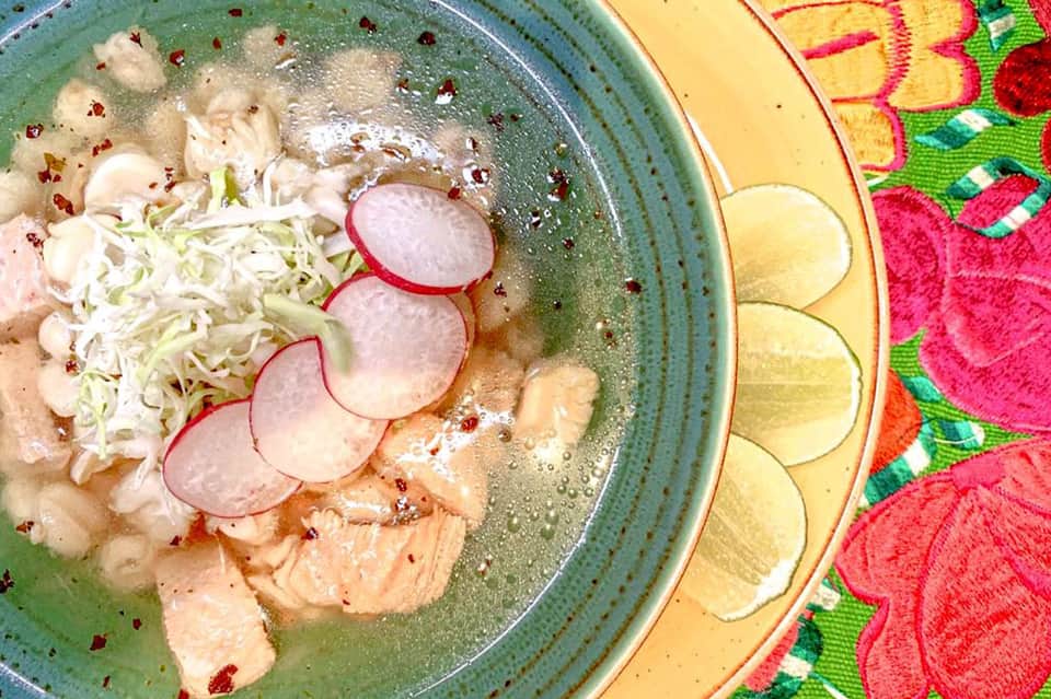 Bowl of Asian noodle soup with radishes and green onions on colorful placemat
