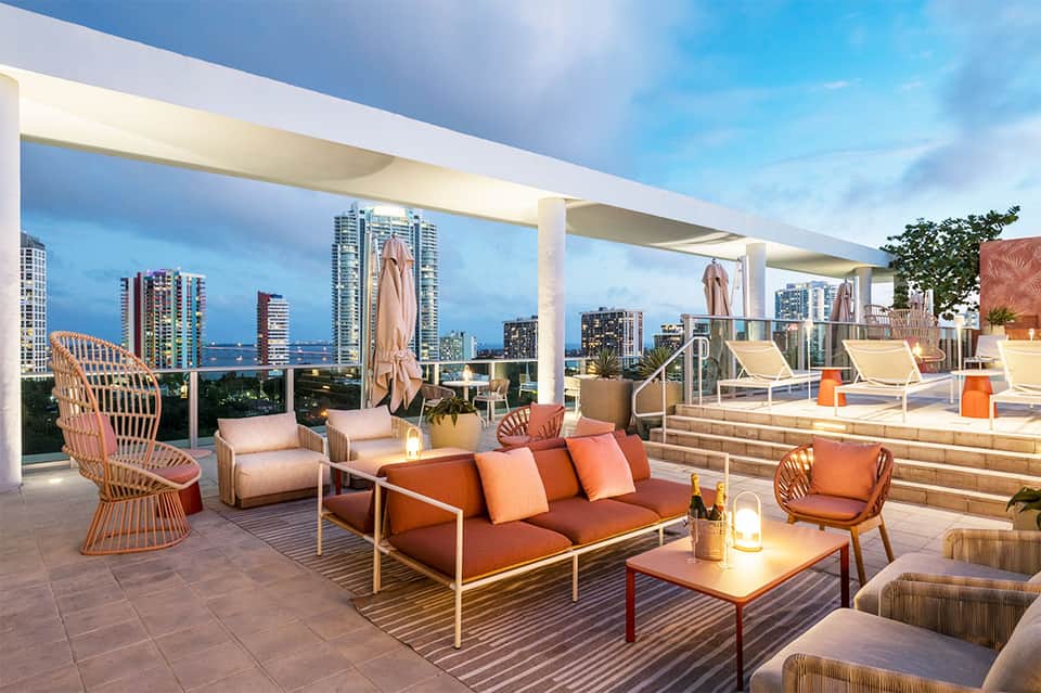 Rooftop lounge with orange seating, city skyline views, and modern architectural design