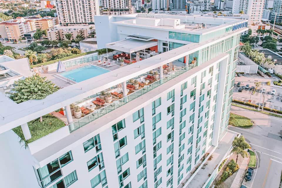 Aerial view of modern hotel rooftop pool and terrace overlooking urban cityscape