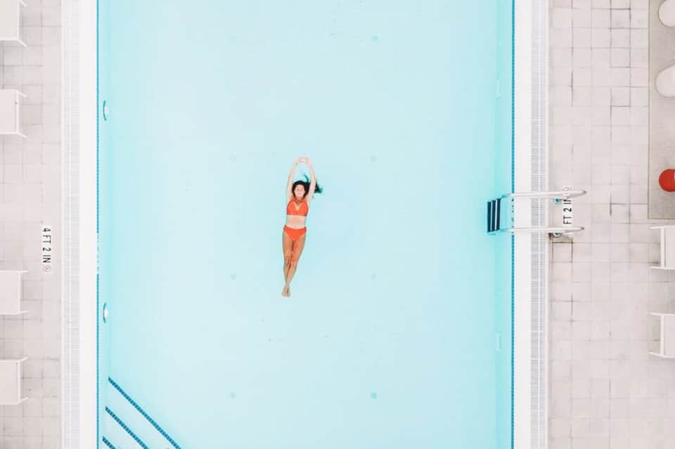Woman floating in light blue indoor lap pool viewed from above