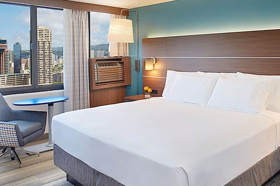 Modern hotel bedroom with city skyline view, wood headboard, and contemporary furnishings
