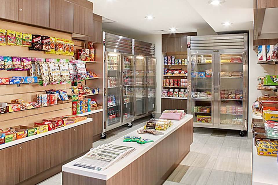 Hotel convenience store interior with colorful snack products on wooden shelves and refrigerated cases