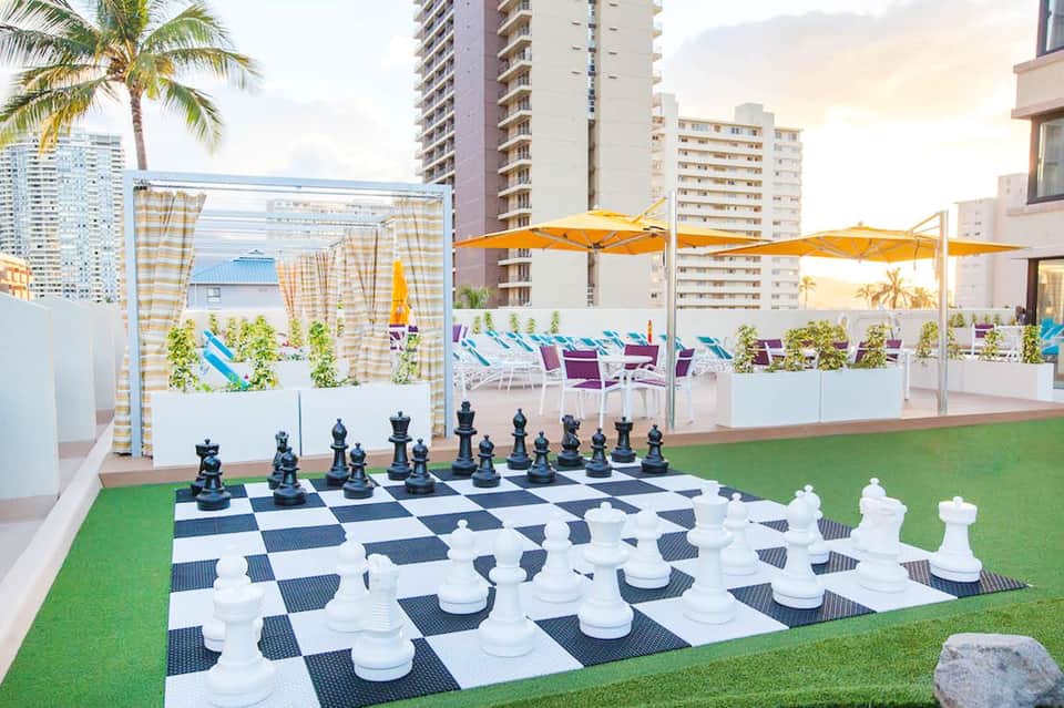 Rooftop terrace with giant chess set, yellow umbrellas, and city skyline views