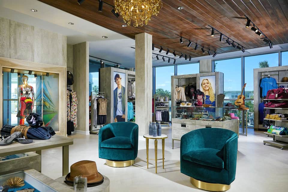 Luxury boutique retail space with teal velvet chairs, designer displays, and natural light from floor-to-ceiling windows
