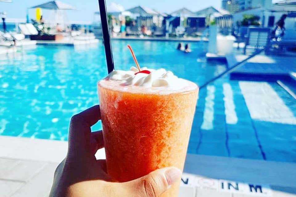 Colorful frozen beverage by the pool with lounge chairs and cabanas in background