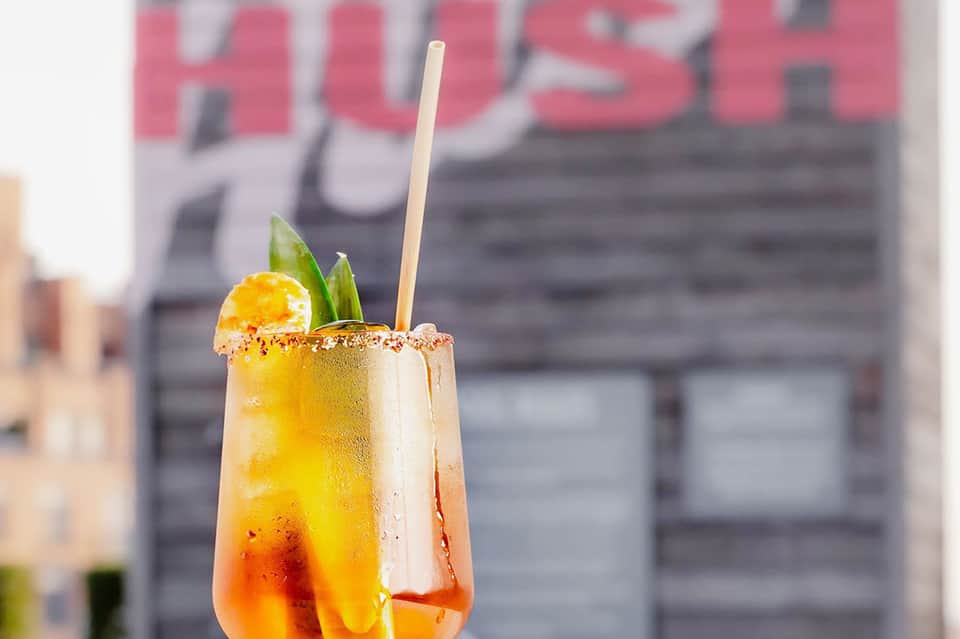 Colorful tropical cocktail with spicy rim in urban setting with blurred signage
