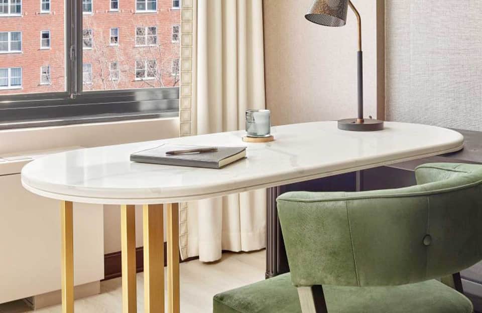 Modern minimalist workspace with oval white desk, green chair, and city view through large window