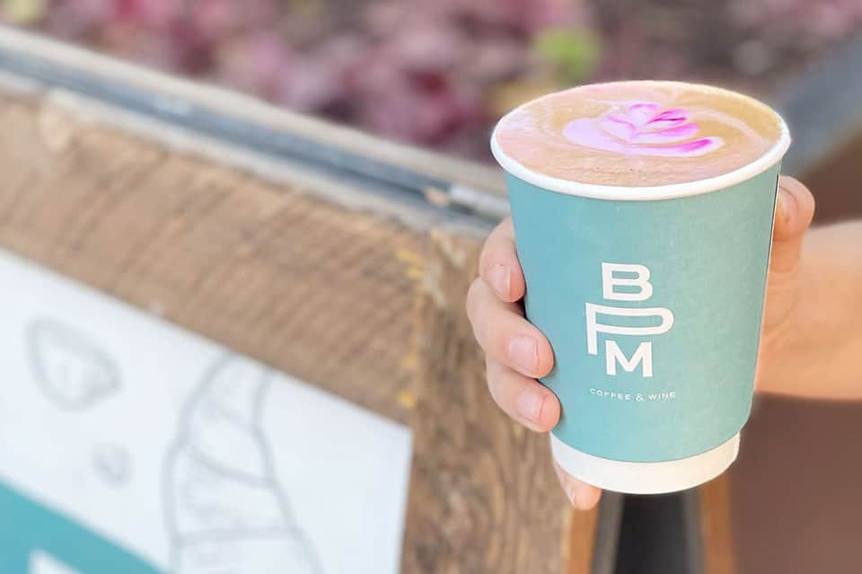 Hand holding a turquoise coffee cup with latte art from BYM Coffee & Wine cafe