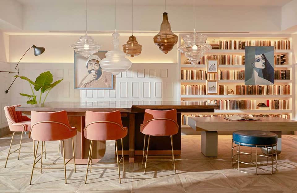 Upscale library lounge with bar seating, pendant lighting, bookshelves, and contemporary furniture