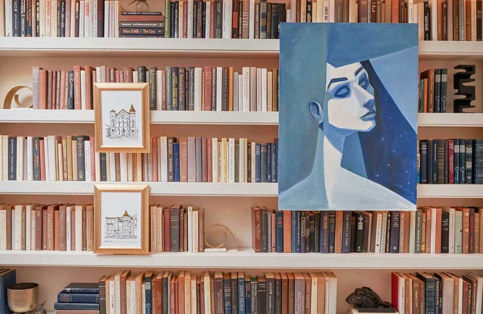 Elegant bookshelf with novels and blue portrait artwork