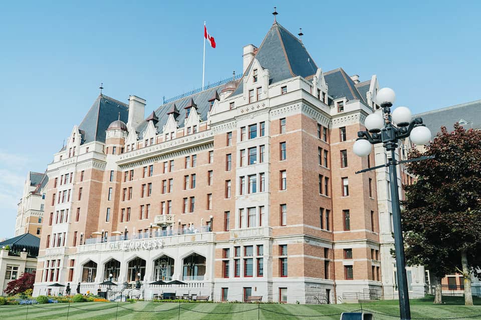 Historic brick hotel building with turrets, Canadian flag, and manicured lawn grounds