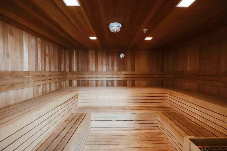 Empty wooden sauna interior with benches and wood paneling throughout