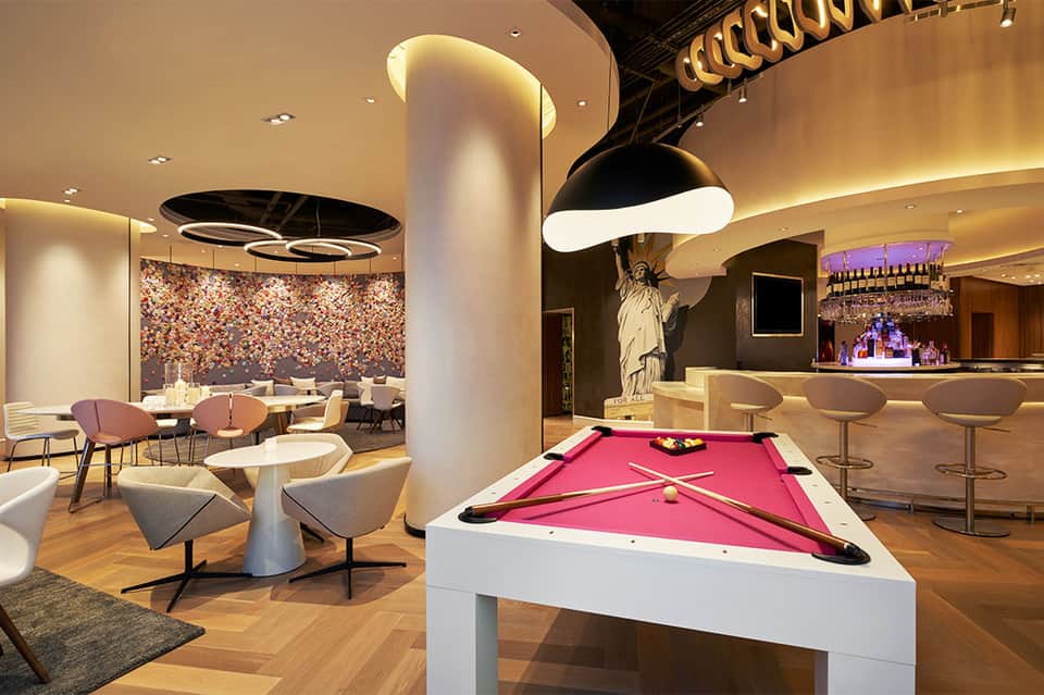 Upscale lounge with pool table, bar area, decorative wall, modern pendant lighting, and seating