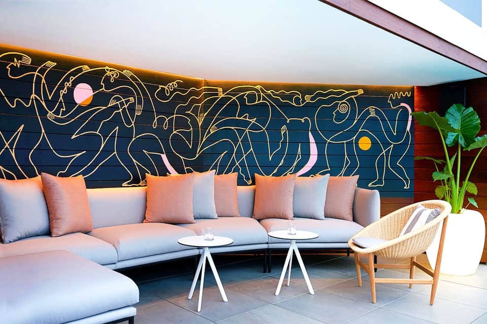 Modern lounge seating area with blue sofa, decorative gold wall art, and accent pillows