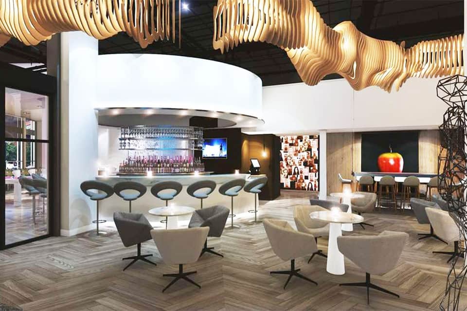 Modern hotel bar lounge with curved ceiling, sculptural gold accents, bar seating, comfortable armchairs, and contemporary artwork
