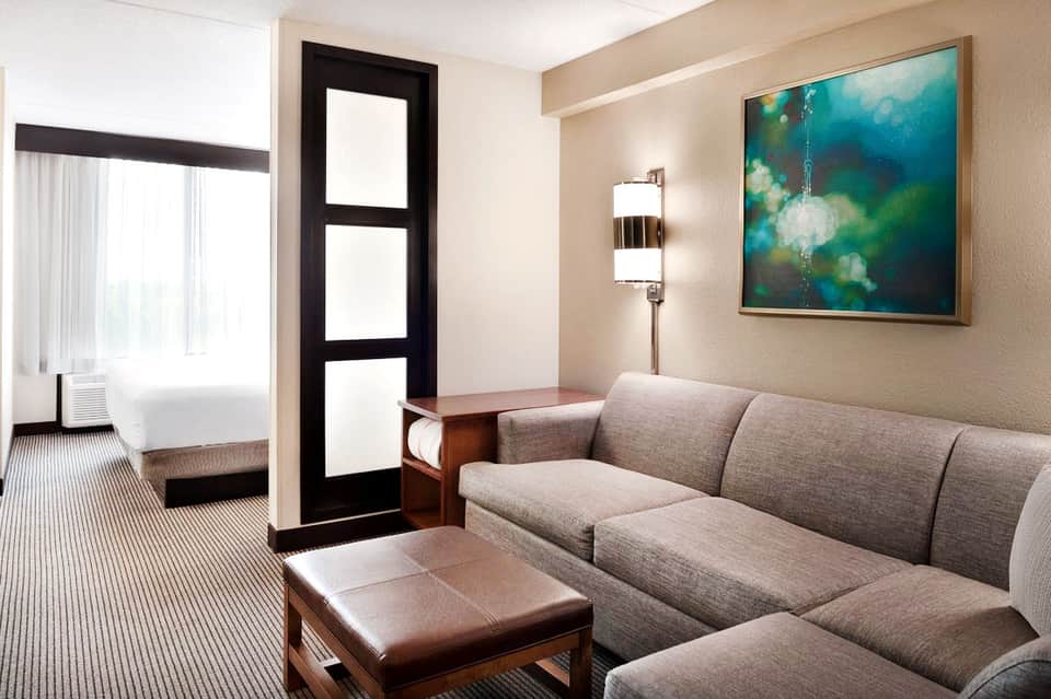 Modern hotel suite with beige sofa, dark accent door, and contemporary artwork