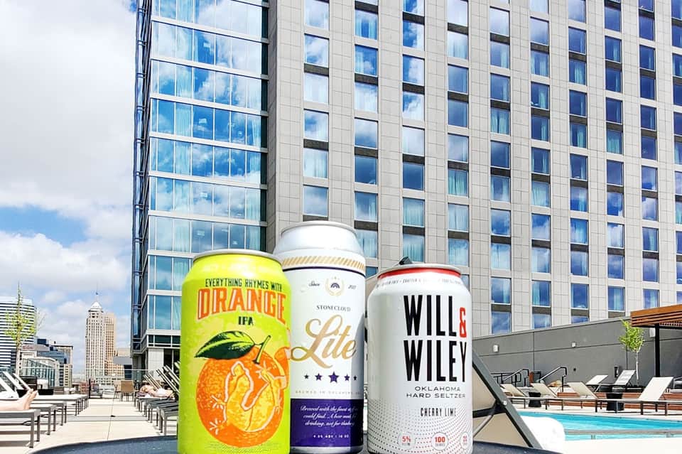 Rooftop bar with craft beers displayed against urban skyline and pool area with lounge chairs