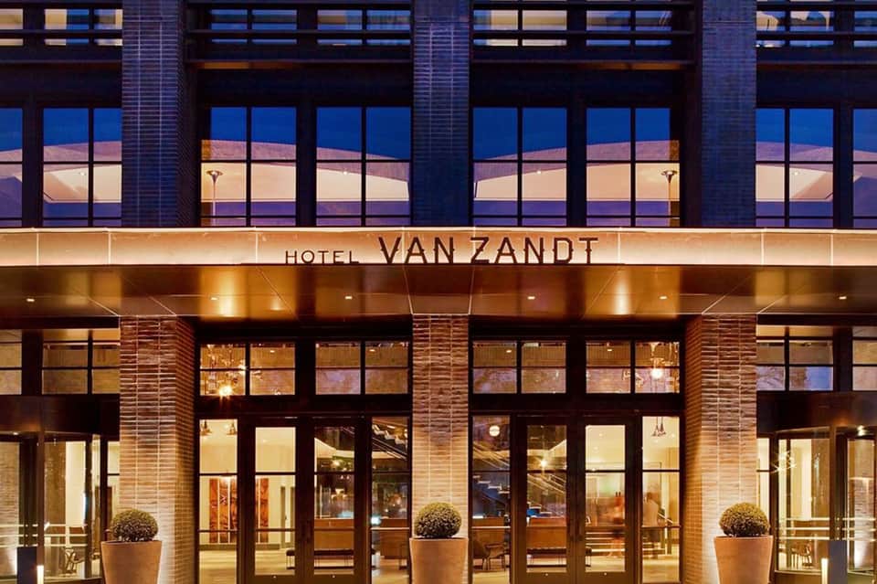 Hotel Van Zandt illuminated facade at dusk with large windows and brick exterior