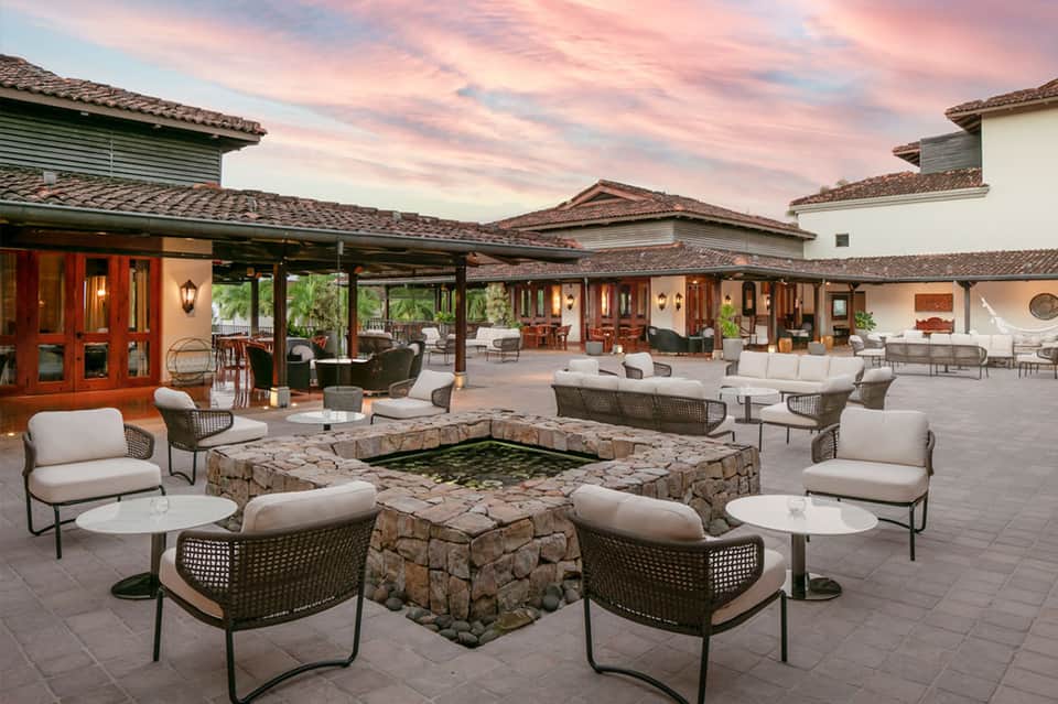 Sunset courtyard with fire pit seating, rustic architecture, and desert mountain backdrop