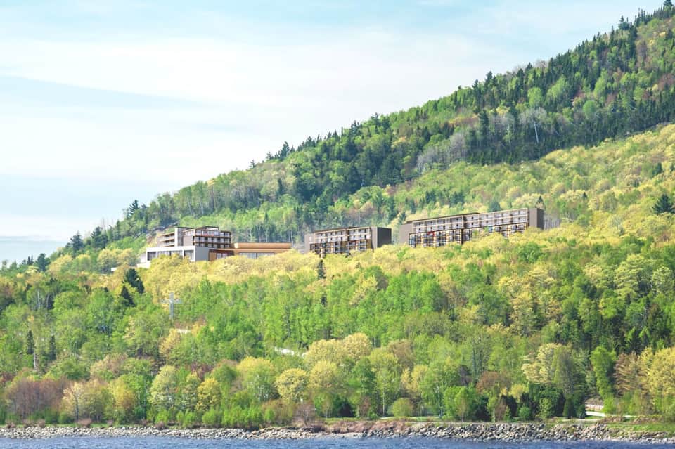Modern resort buildings nestled on a forested hillside overlooking a lake