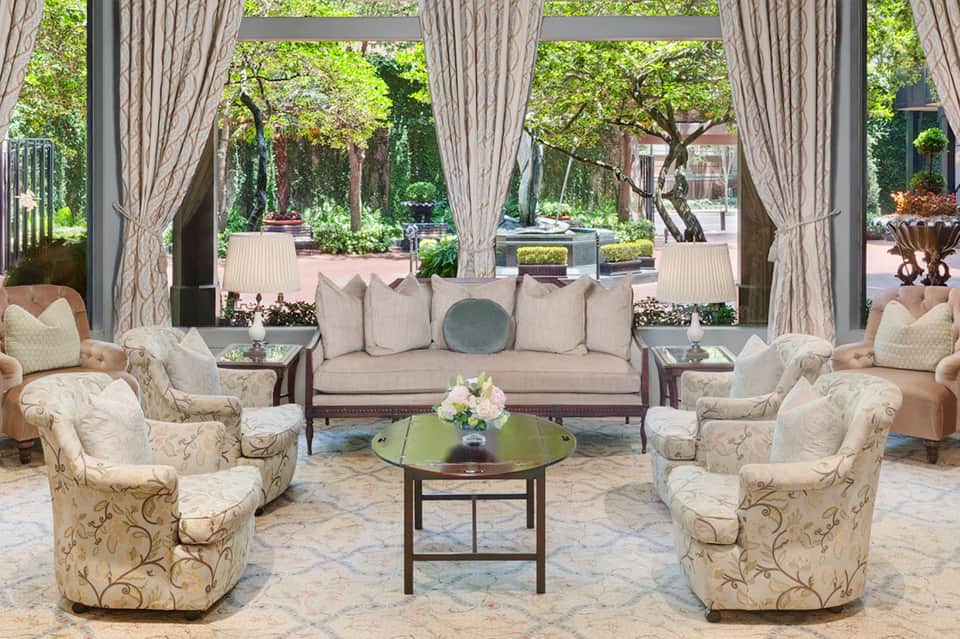 Elegant lounge area with cream furnishings, large windows overlooking manicured gardens