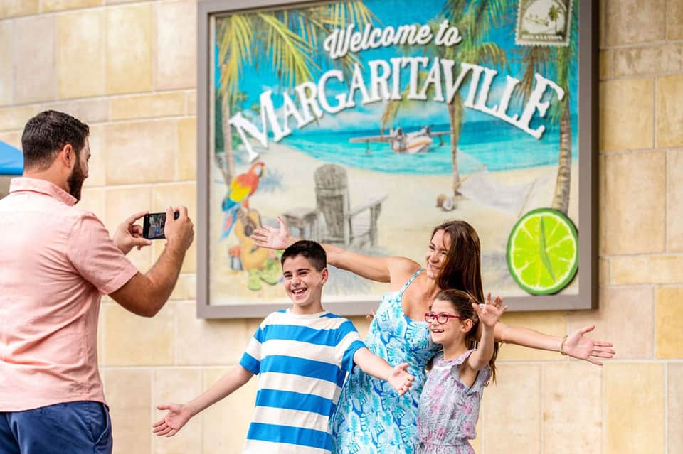 Family posing in front of Margaritaville mural sign inside resort lobby