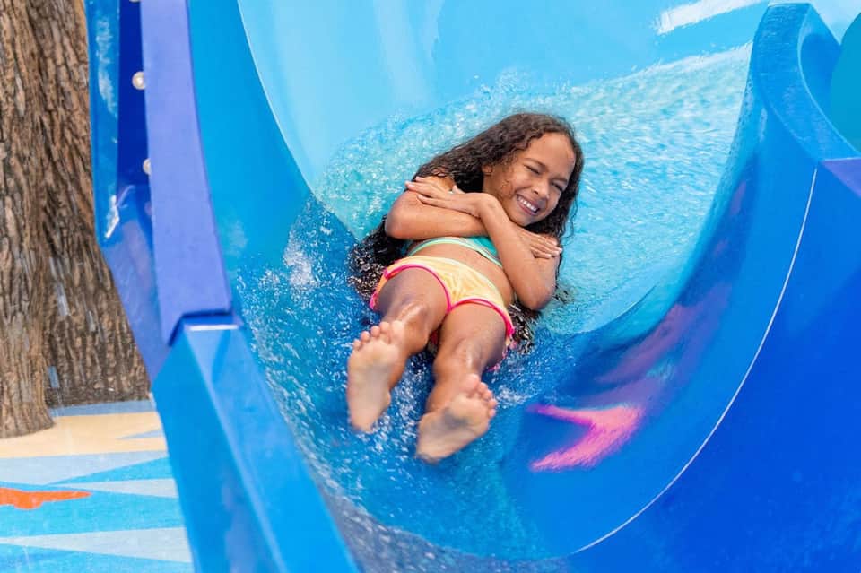 Child enjoying a blue water slide at a resort pool