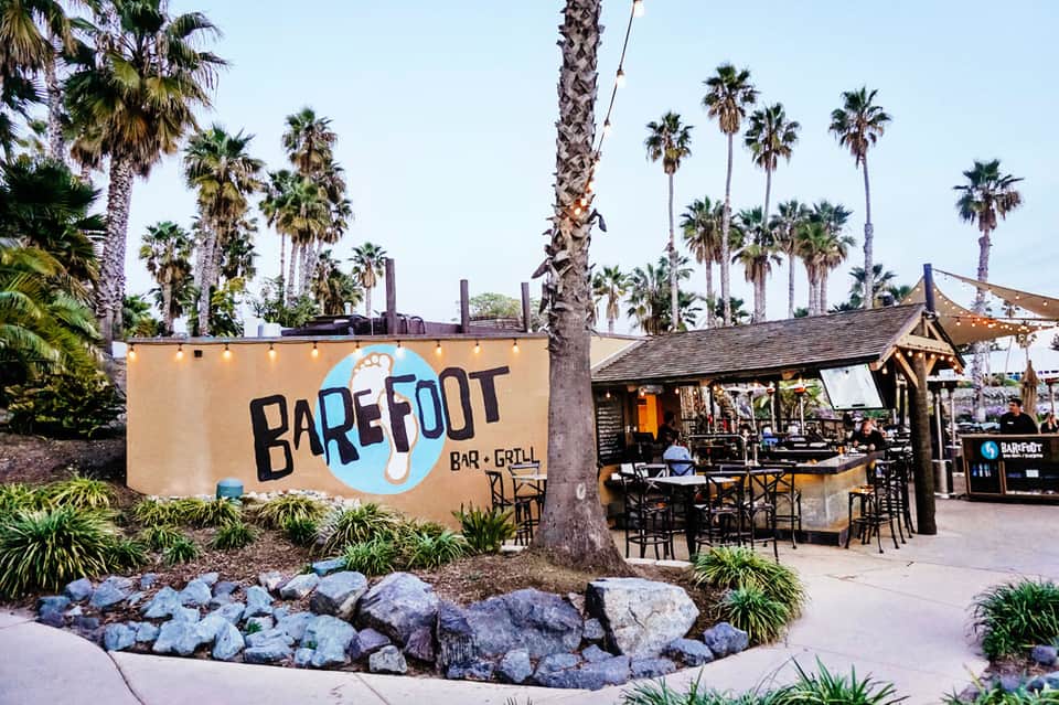 Barefoot Bar and Grill exterior with palm trees and string lights on a coastal patio