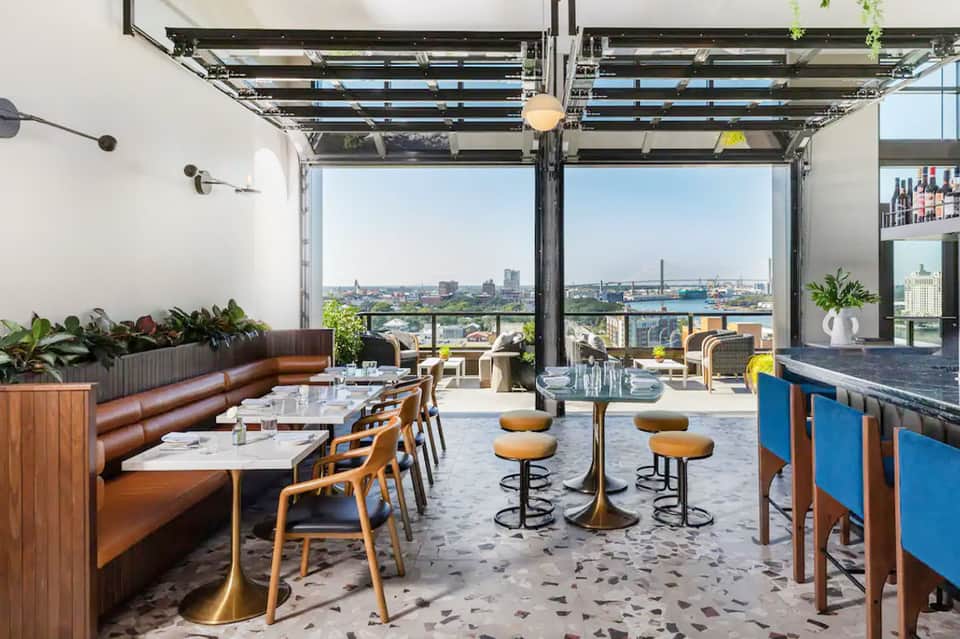 Modern rooftop bar and lounge with city views, leather seating, and floor-to-ceiling windows
