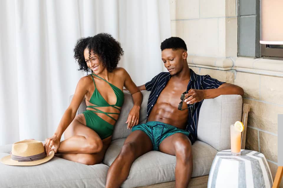 Couple relaxing on hotel suite sofa with ocean view and modern interior decor