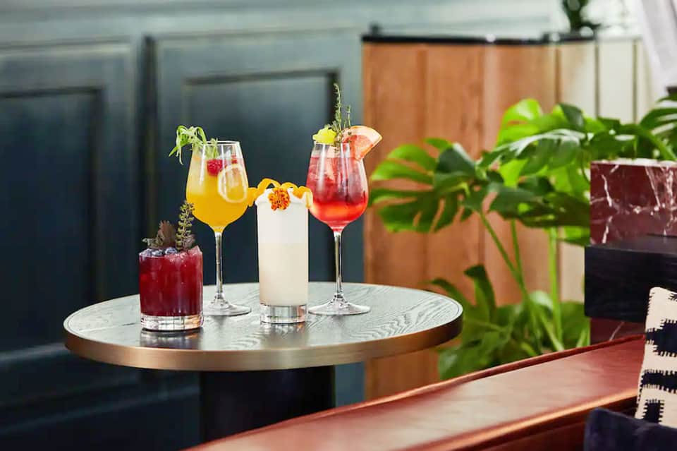 Upscale outdoor lounge with colorful cocktails on a round marble table surrounded by tropical plants