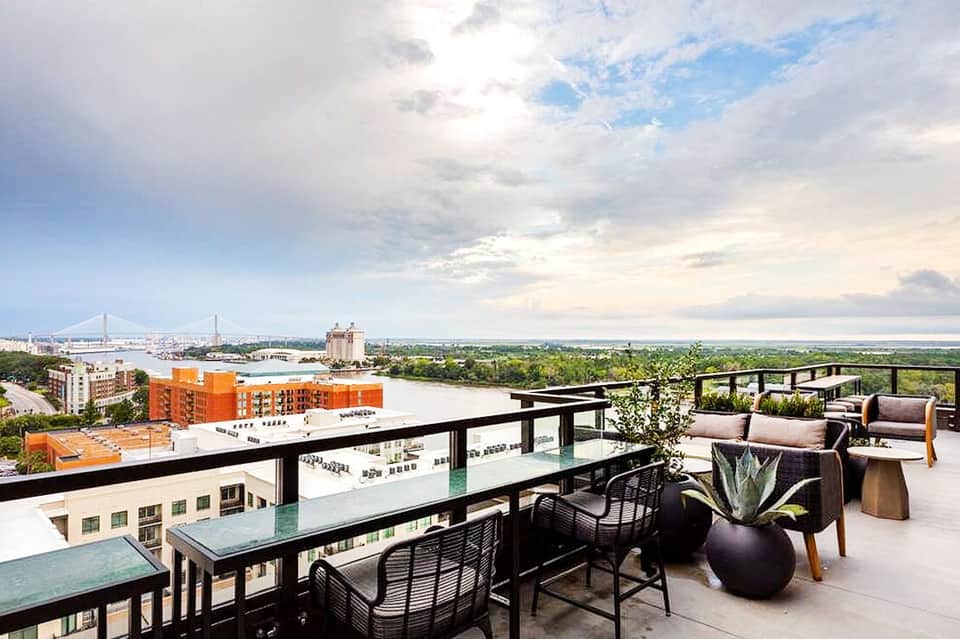 Rooftop terrace with lounge seating overlooking bay and suspension bridge