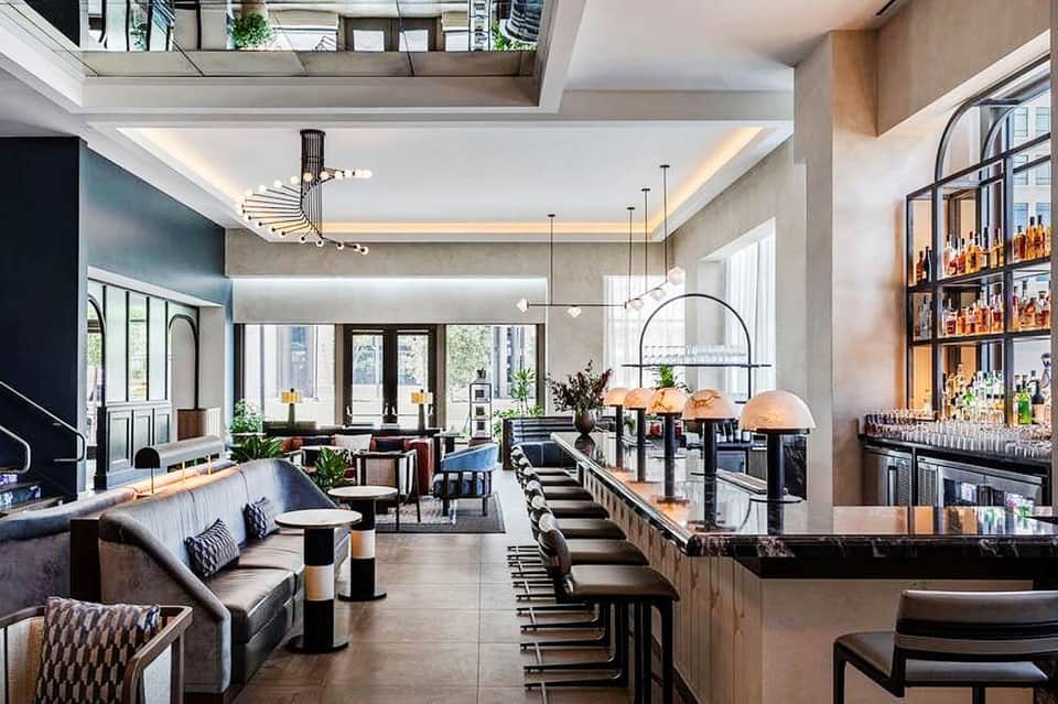 Upscale hotel bar and lounge with high ceilings, contemporary seating, and full bar setup