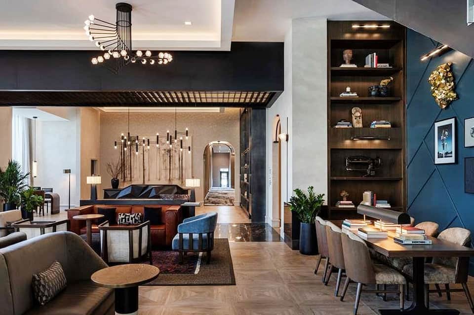 Luxury hotel lobby with high ceilings, modern lighting, leather seating, and blue accent wall