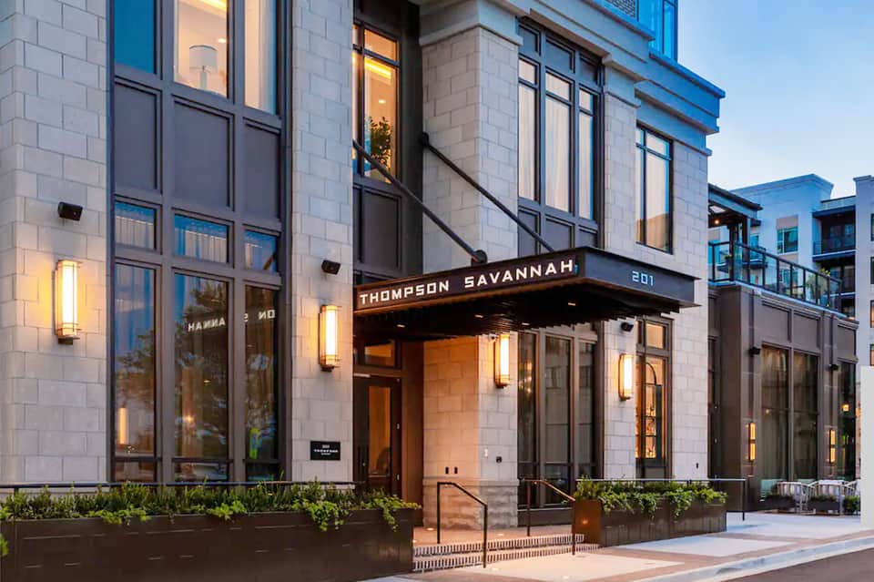 Thompson Savannah hotel entrance with modern architecture, blue accents, and illuminated facade at dusk
