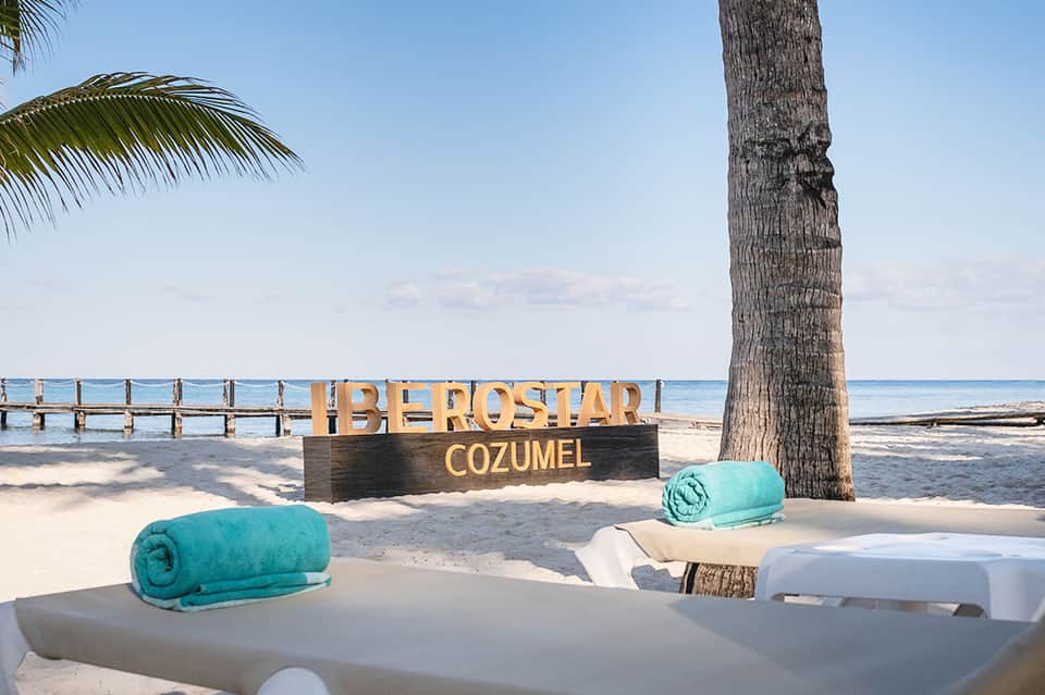Beachfront resort sign with turquoise towels and palm tree in Cozumel