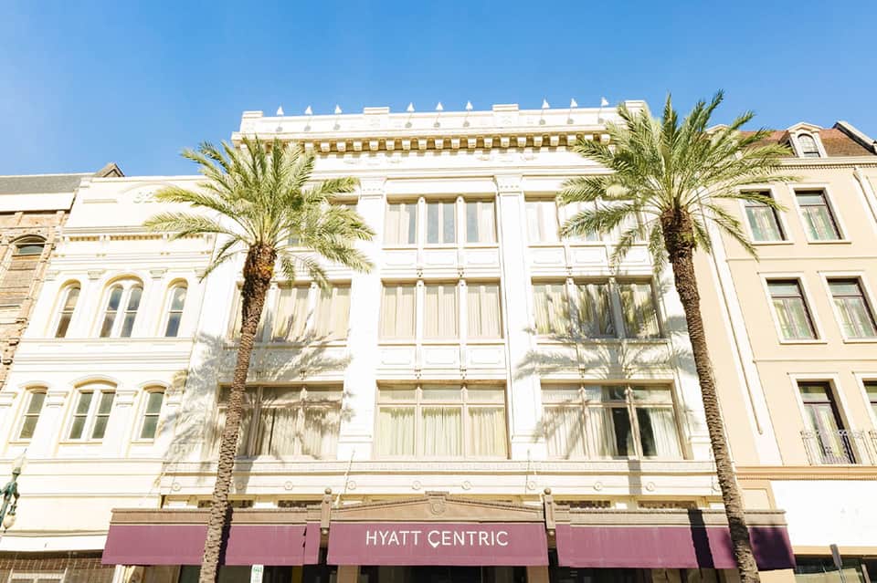 Hyatt Centric historic building facade with white columns and palm trees in bright sunlight