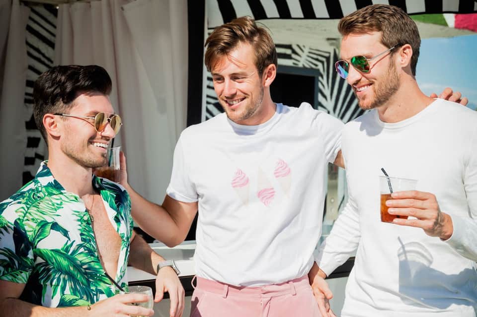 Three men in sunglasses enjoying cocktails at an outdoor summer gathering