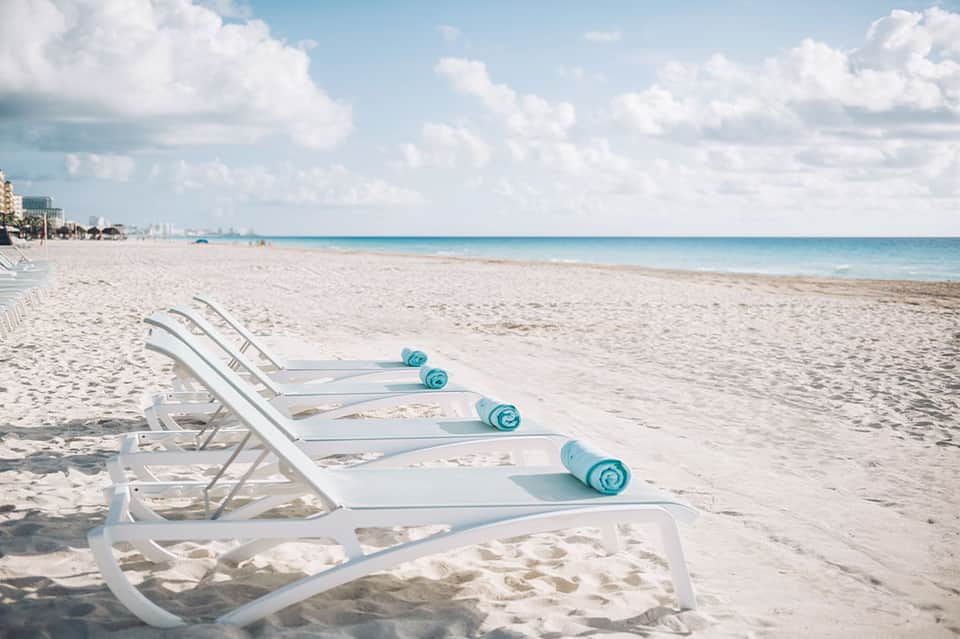 Beach lounge chairs with ocean and buildings visible along coastline
