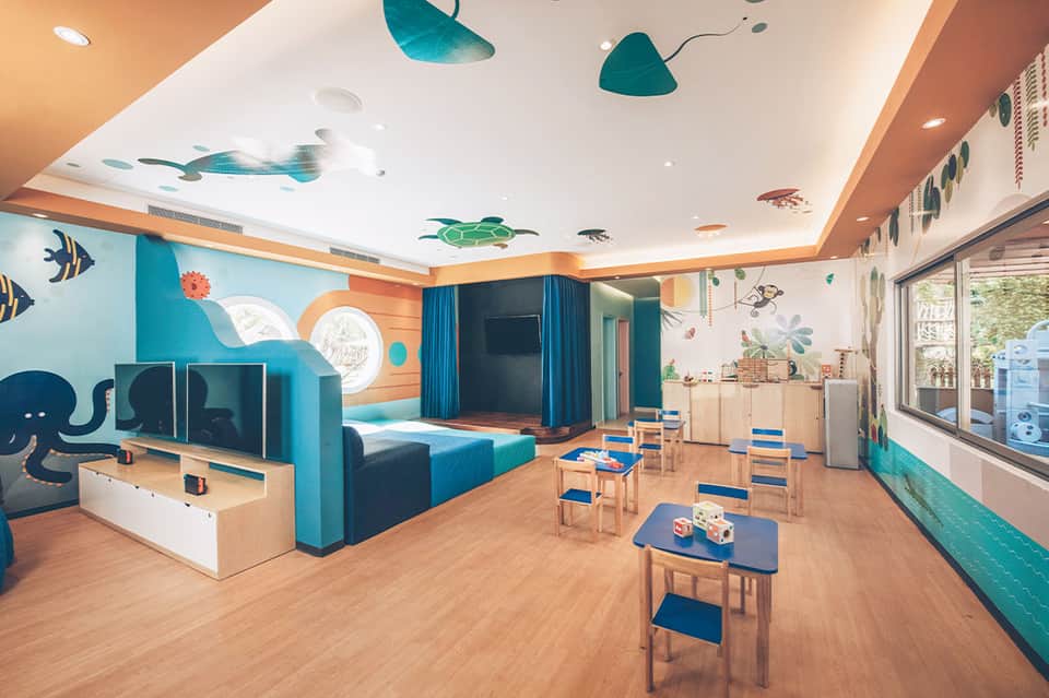 Colorful children's play room with ocean-themed wall art, blue furniture, and educational toys