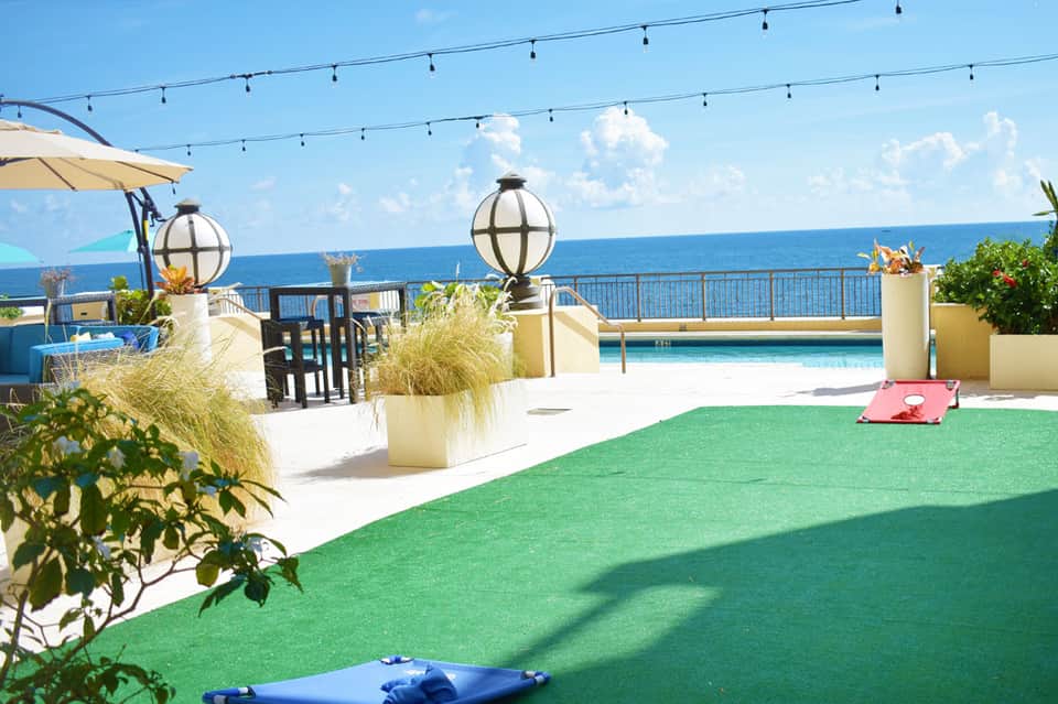 Rooftop terrace with mini golf course, ocean view, pool, and string lights at luxury beachfront resort