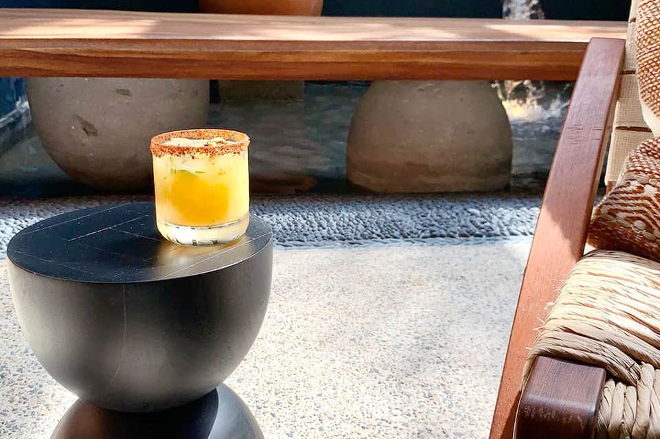 Cocktail with spiced rim on dark side table overlooking resort pool and loungers