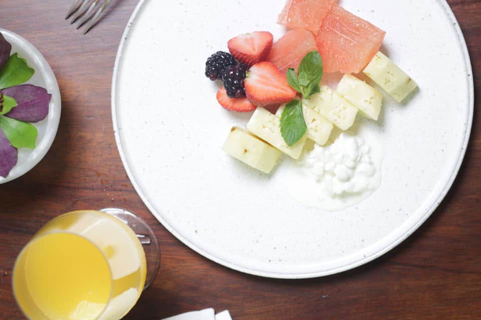 Overhead view of gourmet fruit plate with strawberries, blackberries, smoked salmon, white cheese, and whipped cream