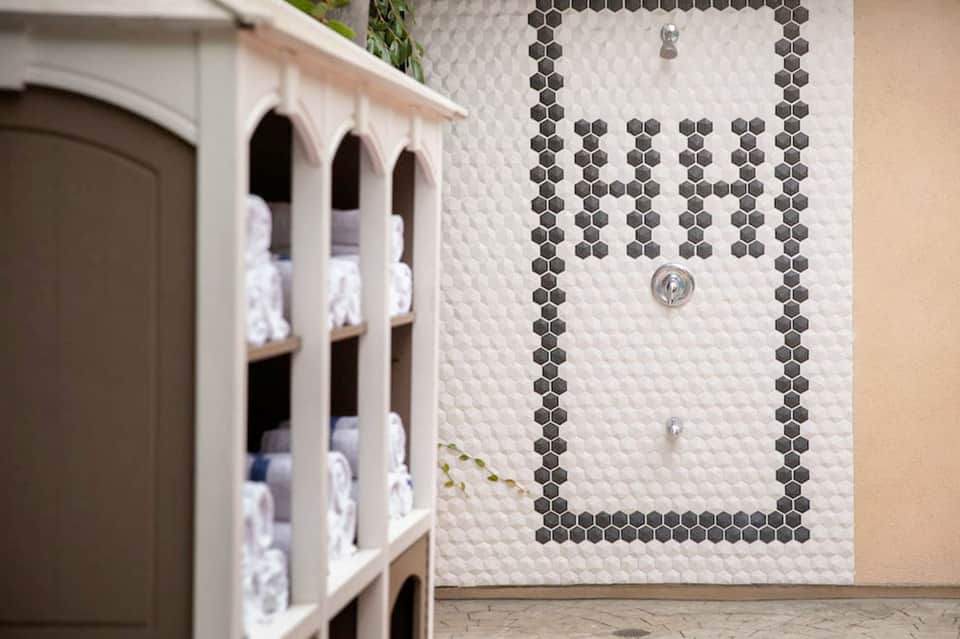 Spa shower with white hexagonal tile wall, black and white stripe border pattern, and chrome fixtures