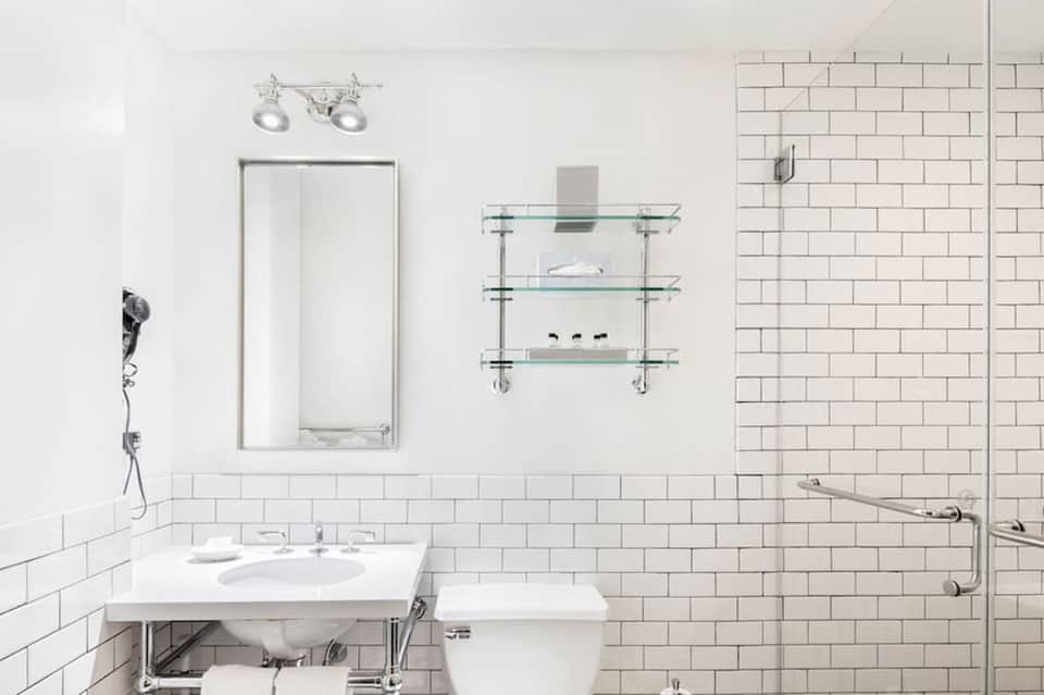 Modern bathroom with white subway tile, vessel sink, large mirror, and glass-enclosed shower