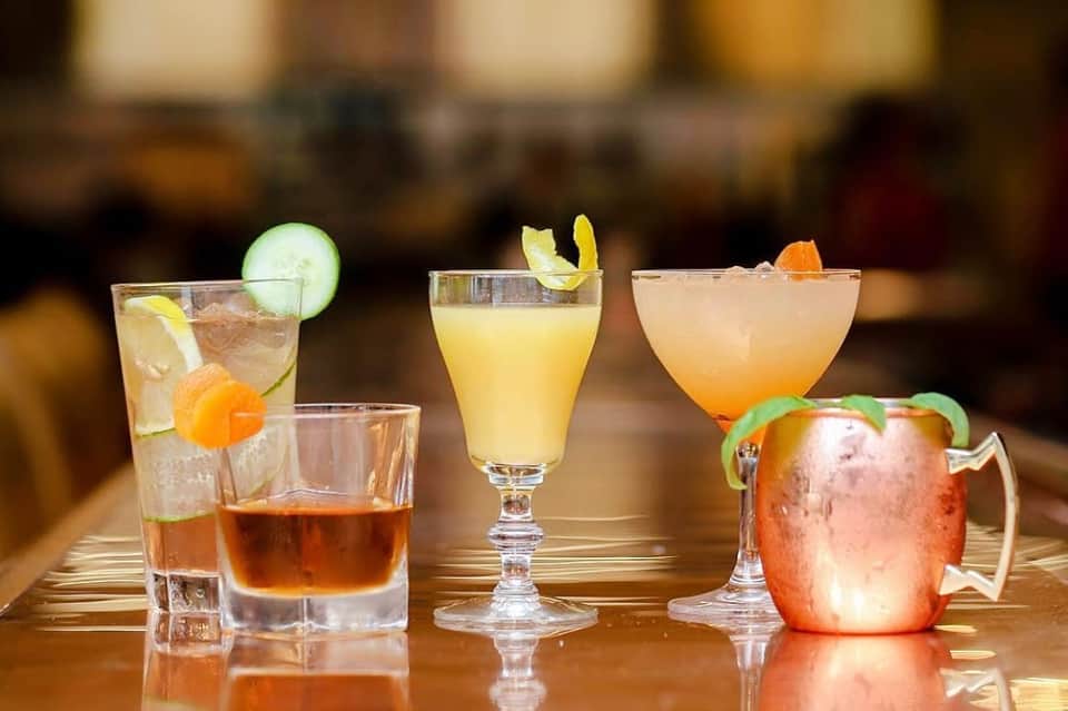 Colorful cocktails with fresh citrus garnishes displayed on a wooden bar counter