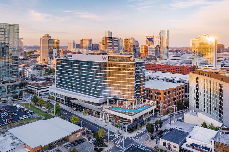 Urban hotel with rooftop pool at sunset, downtown skyline, and surrounding city buildings