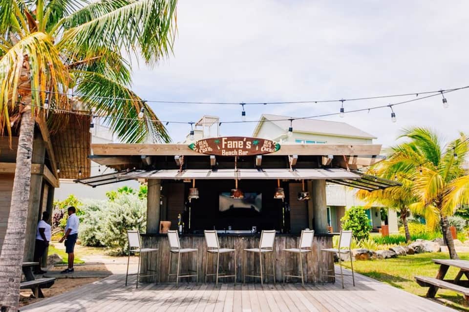 Fane's Beach Bar with thatched roof, palm trees, bar seating, and tropical setting