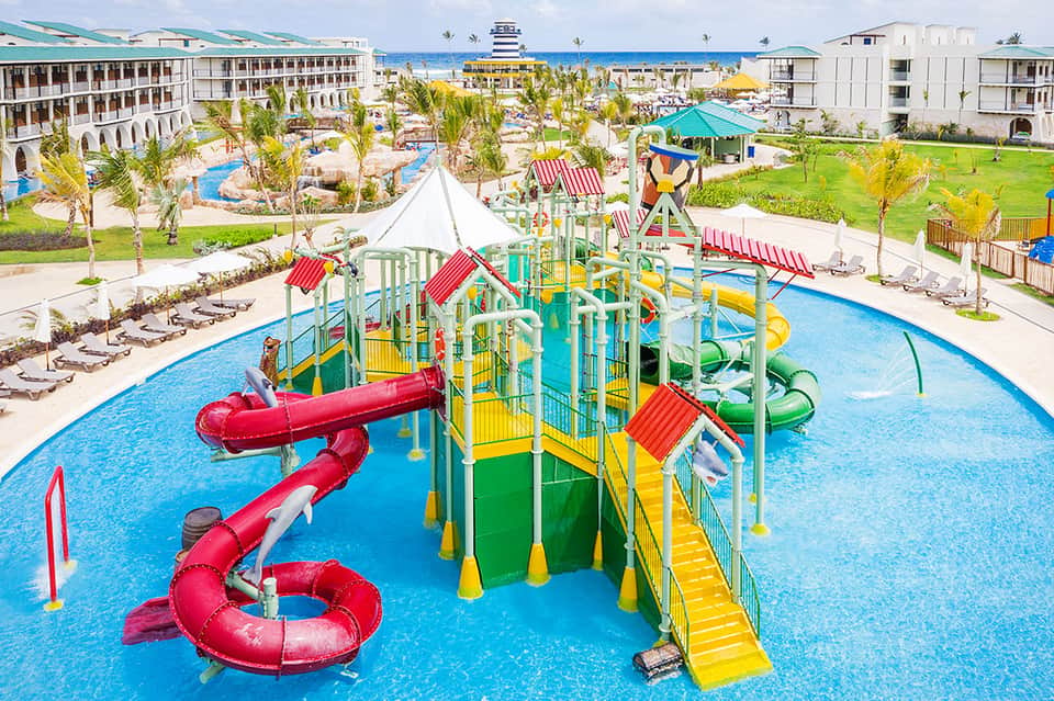 Aerial view of beachfront resort with water park, slides, and colorful playgrounds